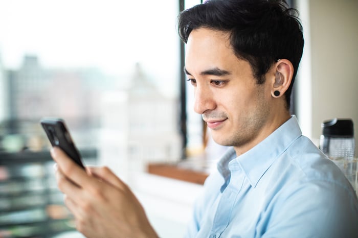 An investor studies something on his phone in an office setting.