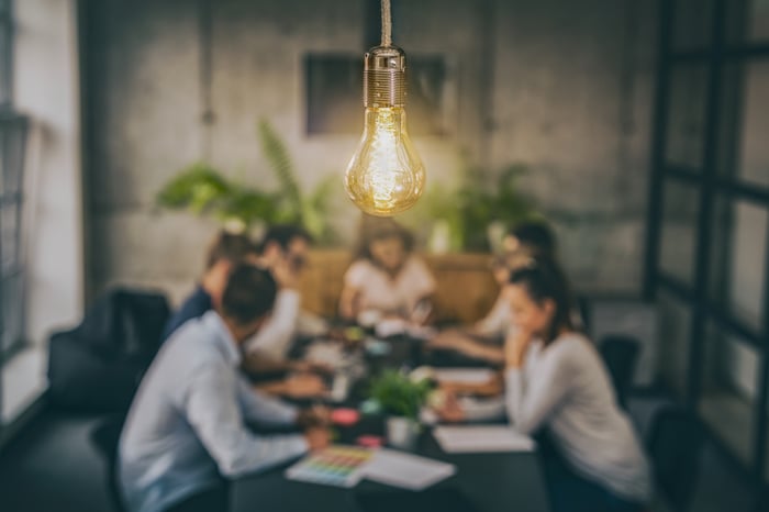 People sitting at a table with a lightbulb in focus. 