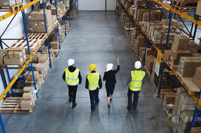 Four people walking in a warehouse.