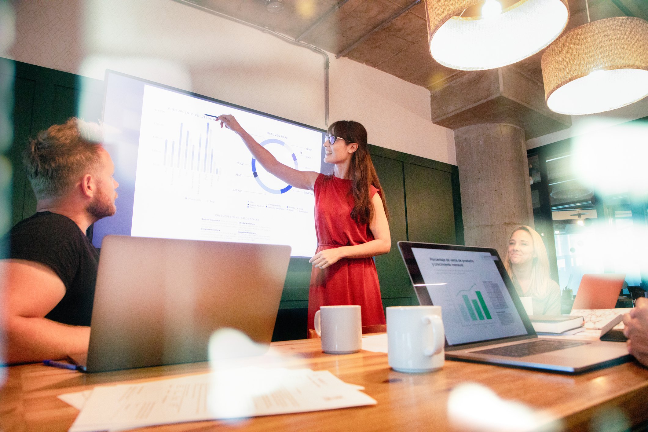 A person pointing to a chart on a screen in a meeting.