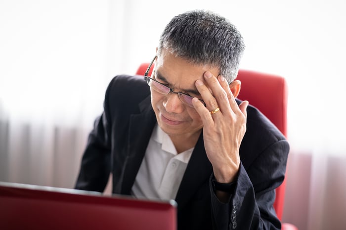 A visibly frustrated office worker with a red laptop.