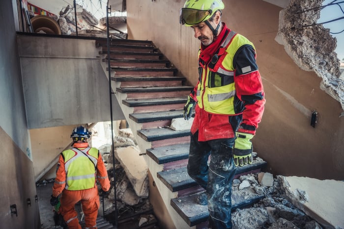 Two people search the rubble of a building after a hurricane