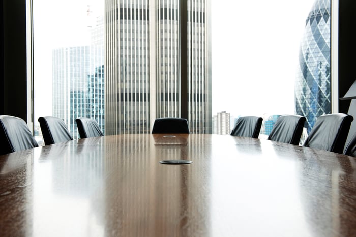 A table and chairs are in an empty boardroom.
