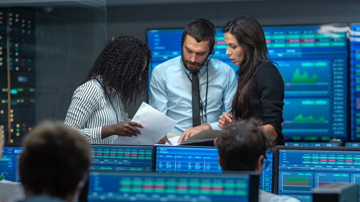 A group of professional stock traders looking at data and conferring.