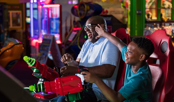 An adult and child playing an arcade game together.