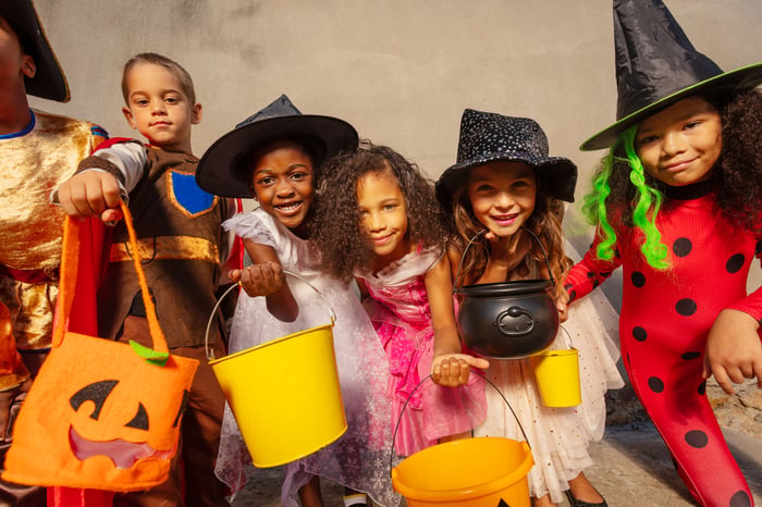 A group of kids hold candy buckets during Halloween.