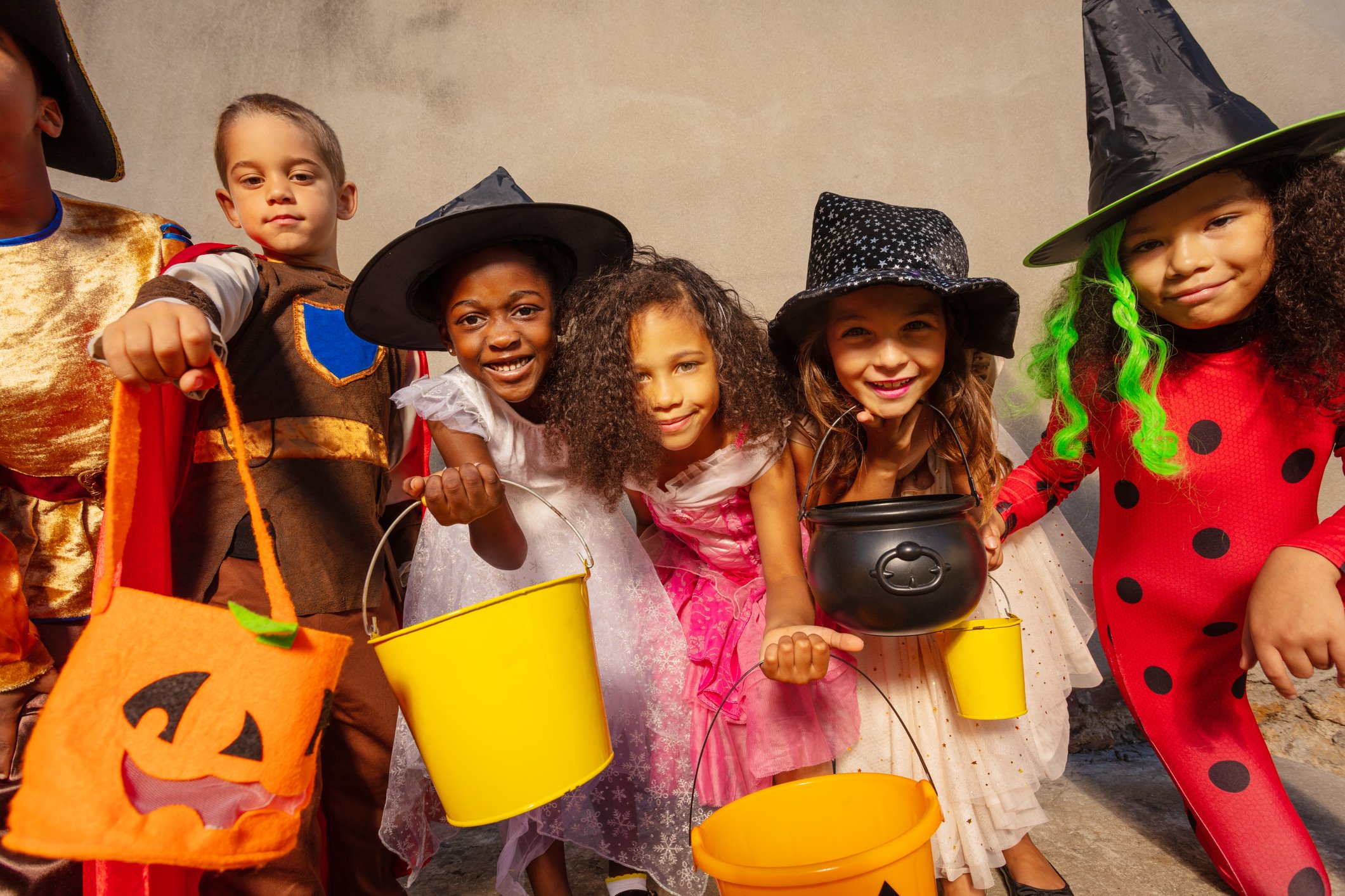 A group of kids hold candy buckets during Halloween