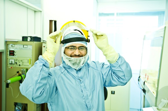 A semiconductor foundry employee prepares to lower their face shield.