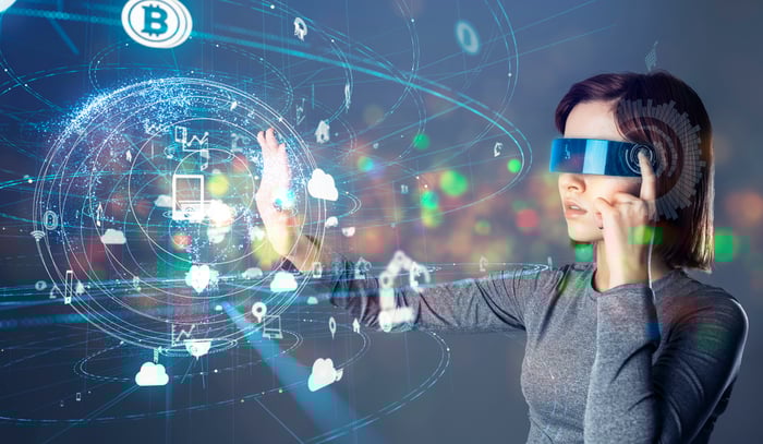 A person wears a virtual reality headset is able to see cryptocurrency coins and other digital widgets.