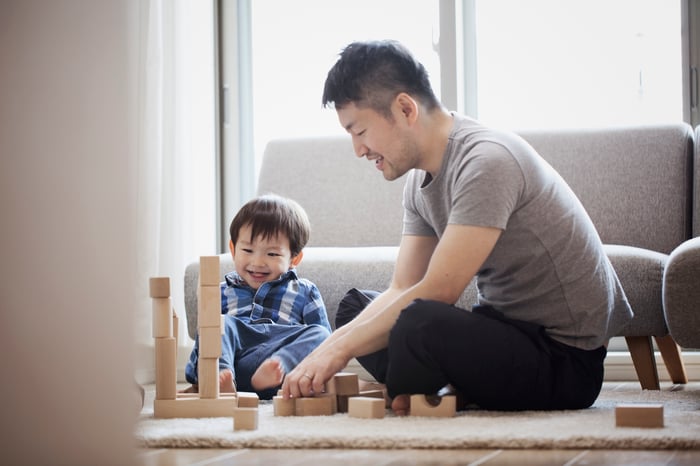 A father and son sitting on the floor and building with blocks.