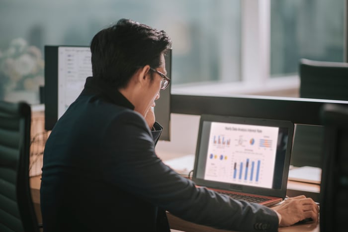 A person looking at charts on a laptop.
