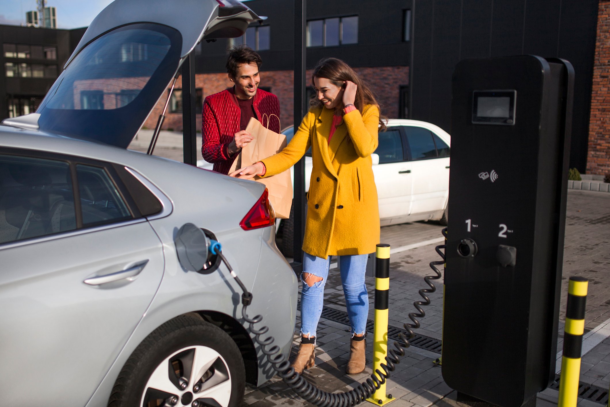EV owner stores shopping bags in trunk as car is charging