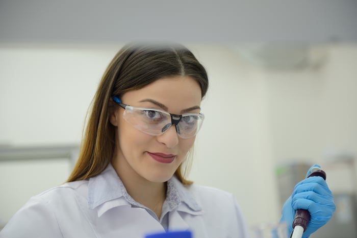 A lab technician using a pipette to transfer liquid samples. 