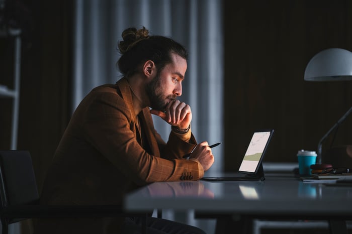 Person sitting in front of a laptop and thinking