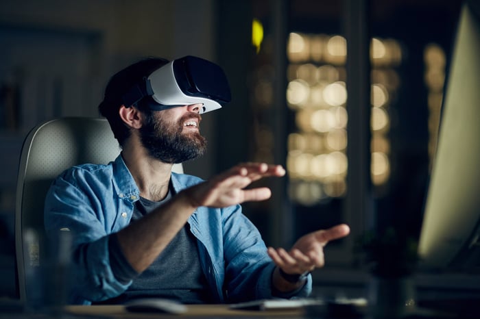 Une personne portant un appareil de réalité virtuelle et interagissant avec des objets du monde virtuel. 