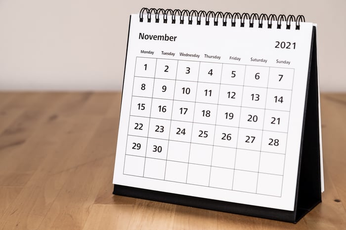 A paper calendar of November 2021 on a wooden table.