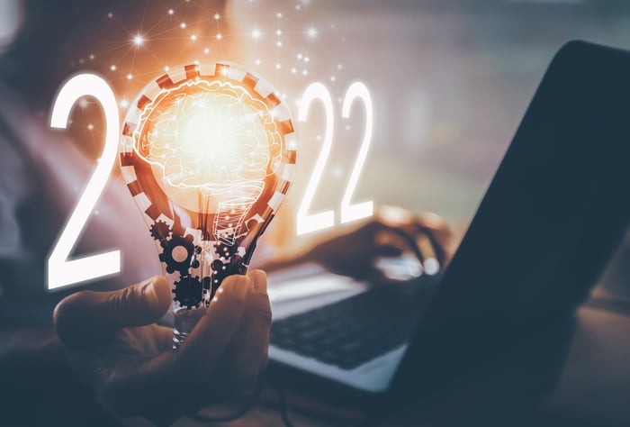 The numbers 2022 and a person holding a lightbulb and using a laptop.