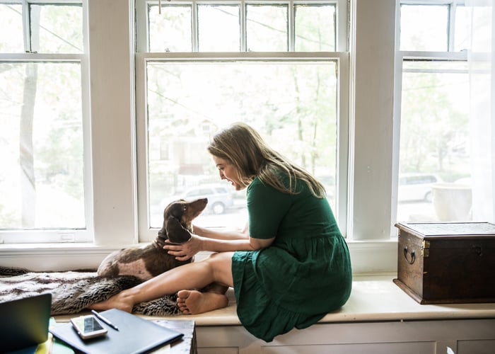 A person sitting with their dog on a window sill.
