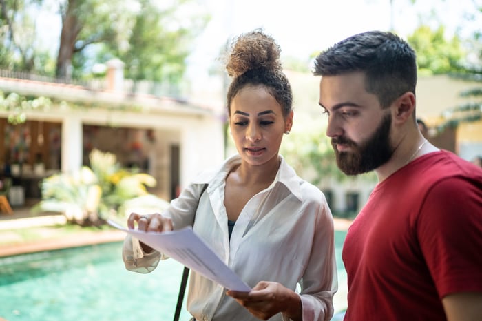 Man and woman outside by pool looking at papers