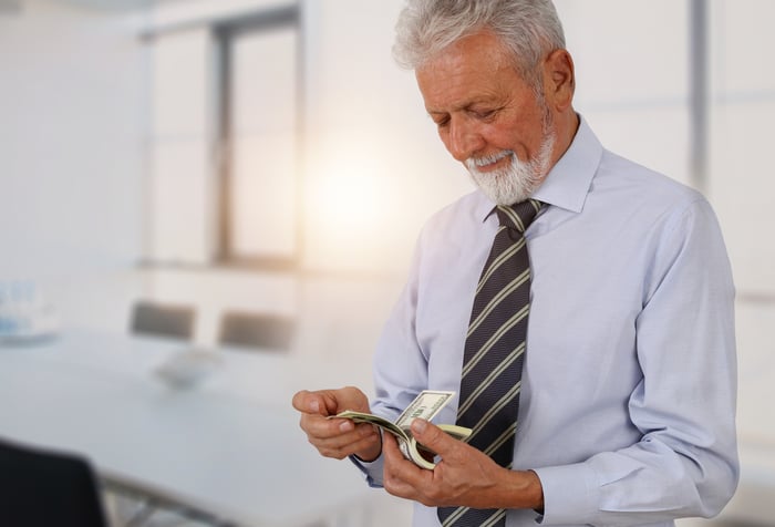 A senior citizen counting a stack of cash in their hands.