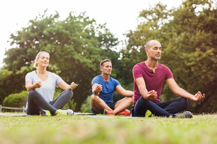 Three people performing yoga poses in a park.