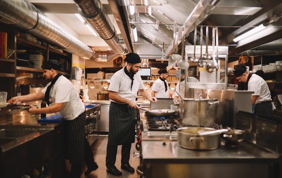 People preparing food in a commercial kitchen.