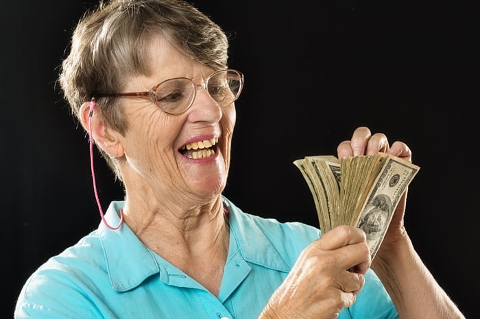 Someone smiling broadly while counting a wad of bills.