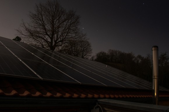 Solar panels installed on a roof are facing the night's sky.