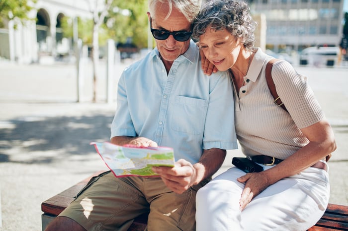 A couple sitting on a bench looking at map.