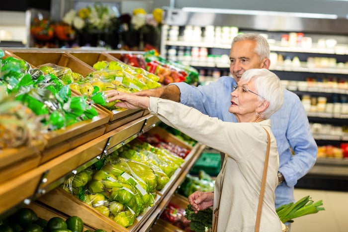 Two people in supermarket produce section.