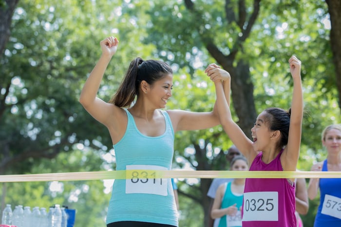 Parent and child reaching the finish line in a race.