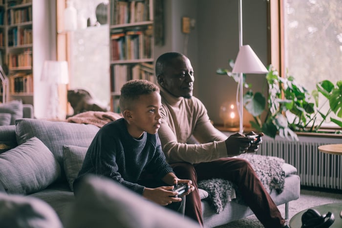 An adult playing video games with a child. 