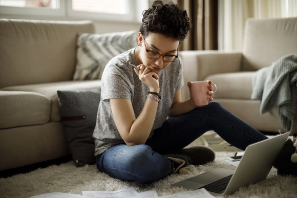 Person sitting on floor in front of laptop looking at documents