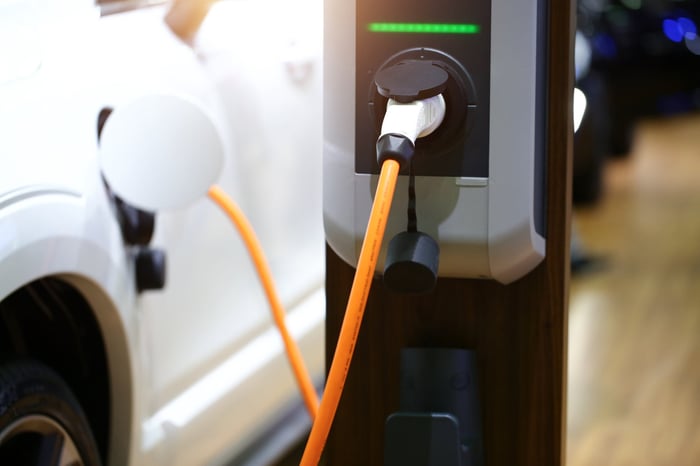 Electric vehicle plugged into charging station.