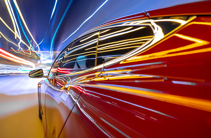 Lights streak down a red electric car racing down the highway.