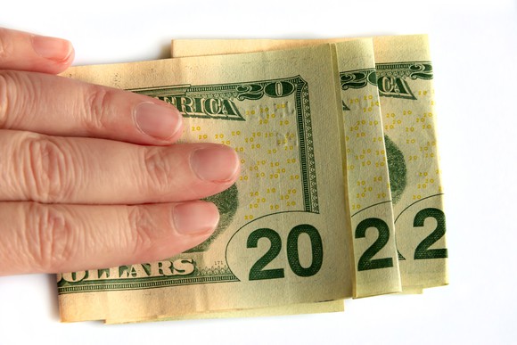 A person holding folded money, with the edges of the bills reading 2022.