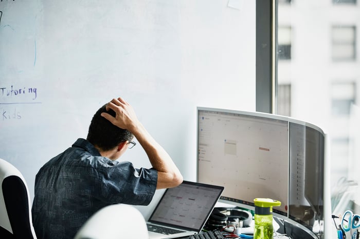 Person scratching his head while looking at a computer.