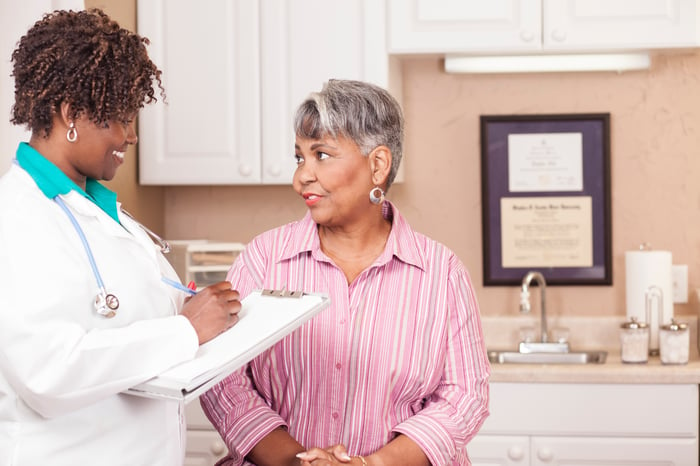 A doctor with a patient jotting down notes.