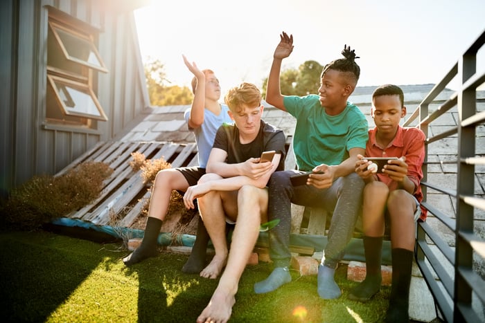 Four teenagers using smartphones to play games.