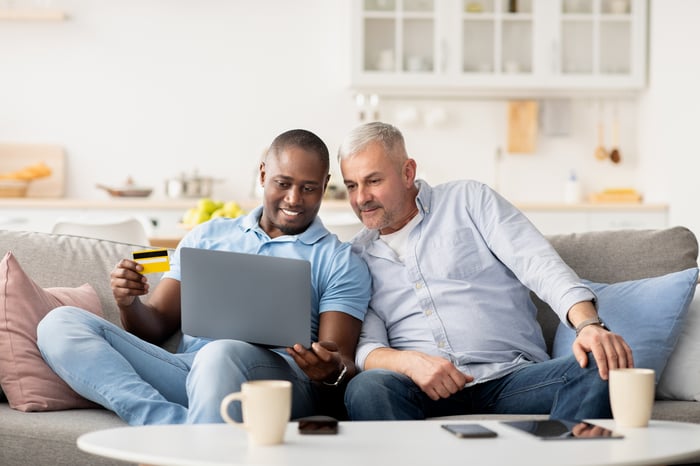 Two people shop online on a laptop.