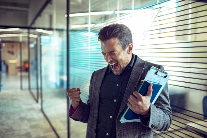 Person holding a book and clipboard, cheering.