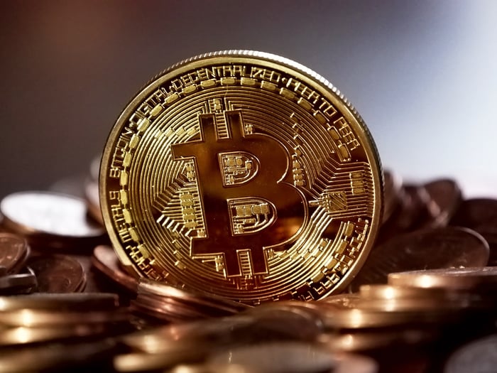 A close-up of a physical gold-colored Bitcoin stood on its side.