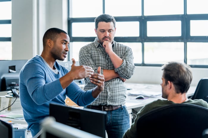 Three people in an informal meeting in an office.