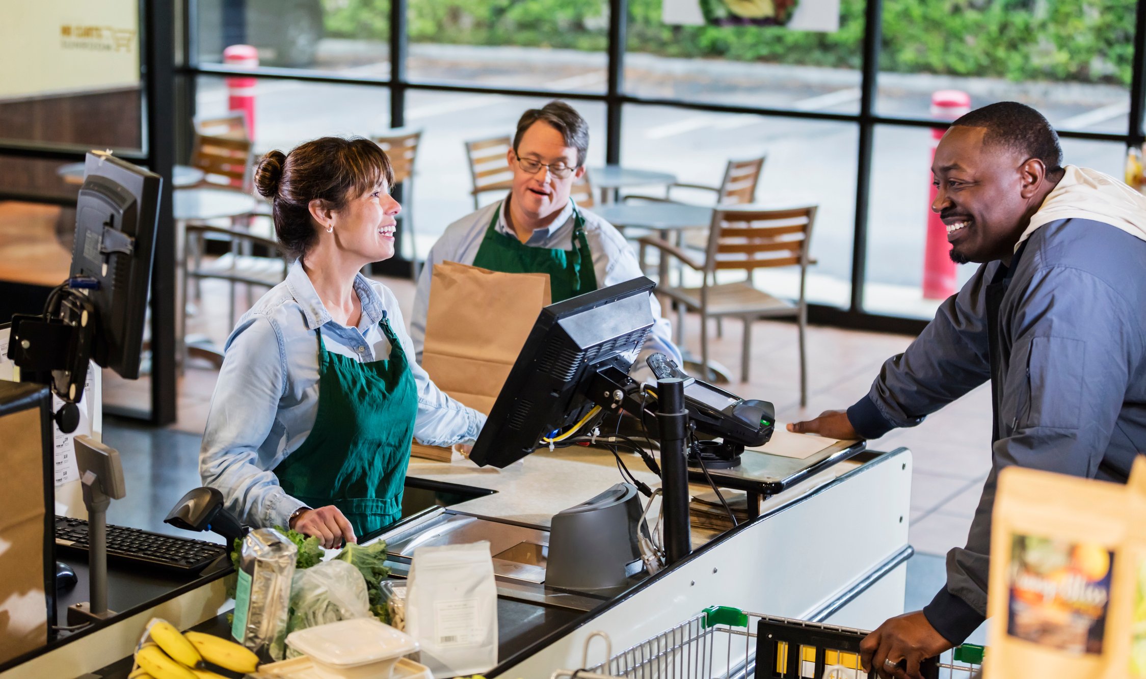 22_01_10 A person checking another person out at a grocery store with a person bagging _GettyImages-1174658807