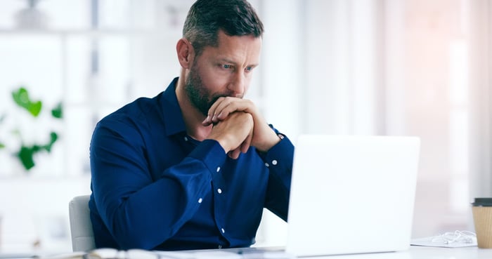 A person with a serious expression at a laptop.