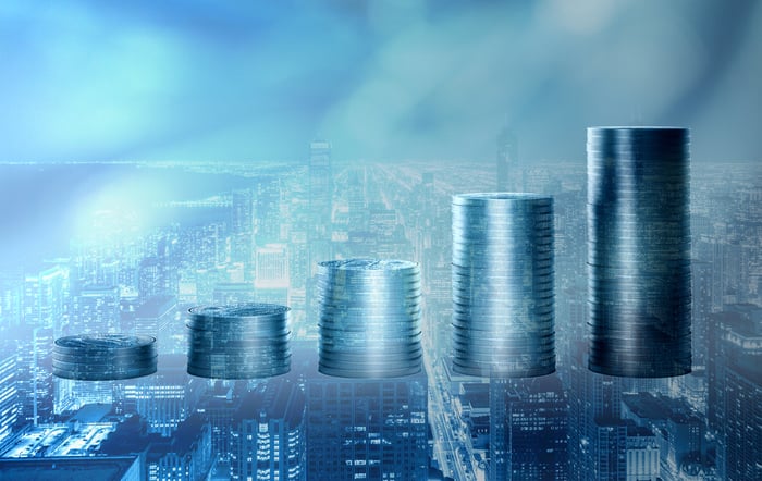 Rising stacks of coins with buildings in the background.