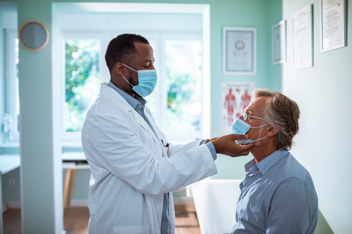 A masked doctor examining a masked patient.