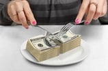 Woman cutting a stack of money -- GettyImages-655044510
