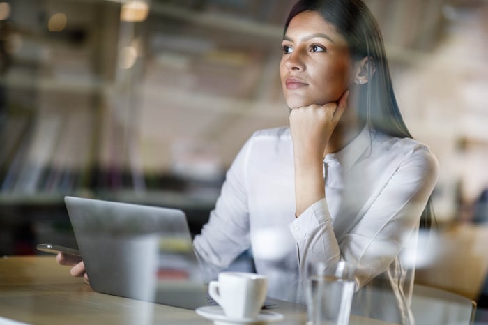 A person looking pensive while sitting at a laptop.