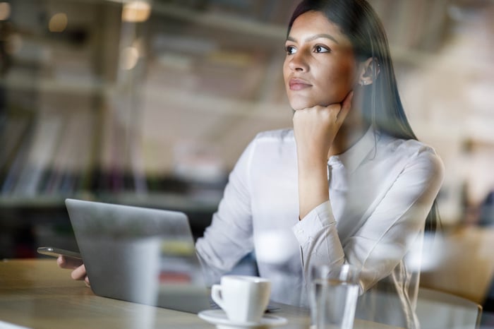 A person looking pensive while sitting at a laptop. 